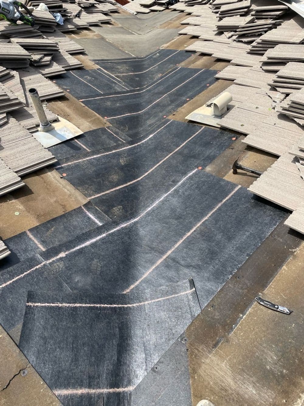 Roofing materials and underlayment being installed on a construction site roof.