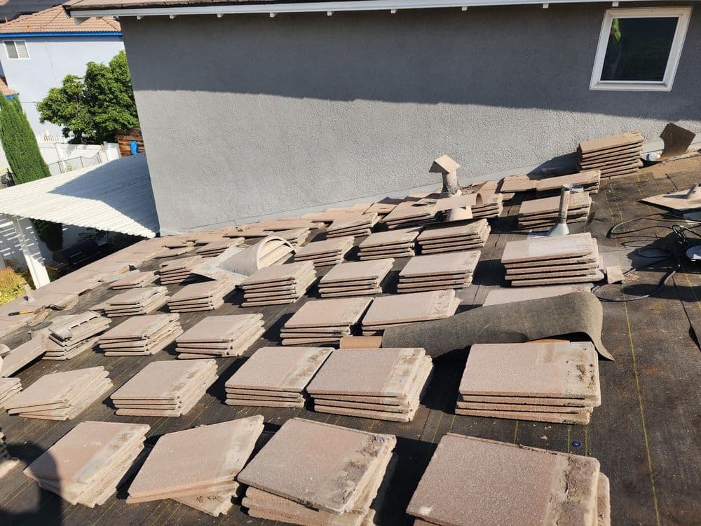 Flat roof covered with stacked tiles, showcasing a residential property under renovation.
