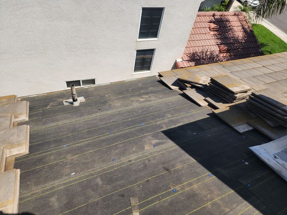 Flat roof of a building under renovation, showcasing roofing materials and yellow lines for alignment.