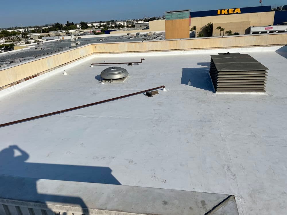 Flat roof of a commercial building with ventilation systems and an IKEA store in the background.
