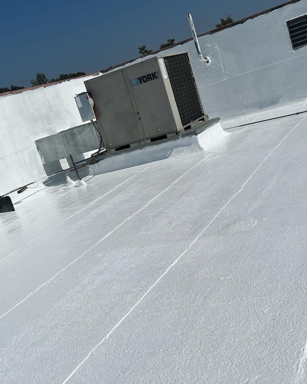 Rooftop with white reflective coating and an air conditioning unit by York.