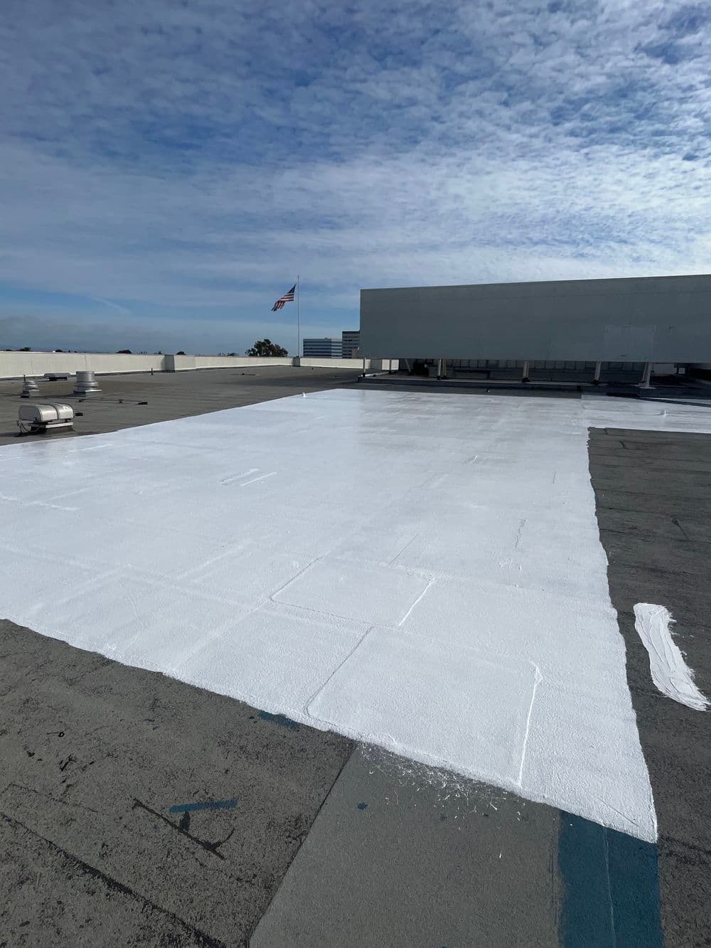 Freshly coated white roof with American flag in background and blue sky above.