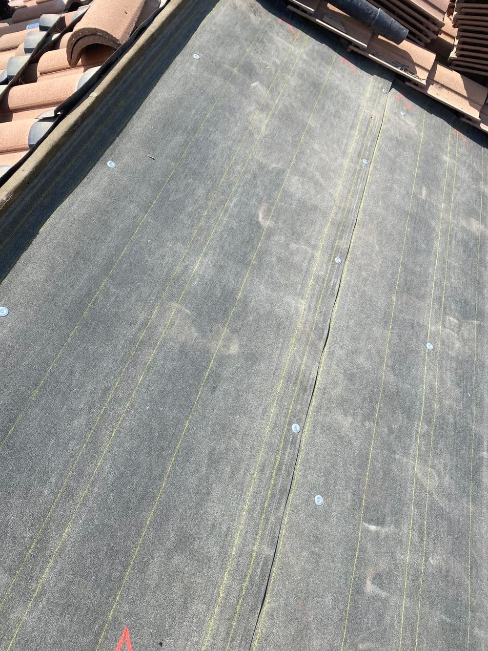 Roofing underlayment installation with marked lines, ready for tile placement.