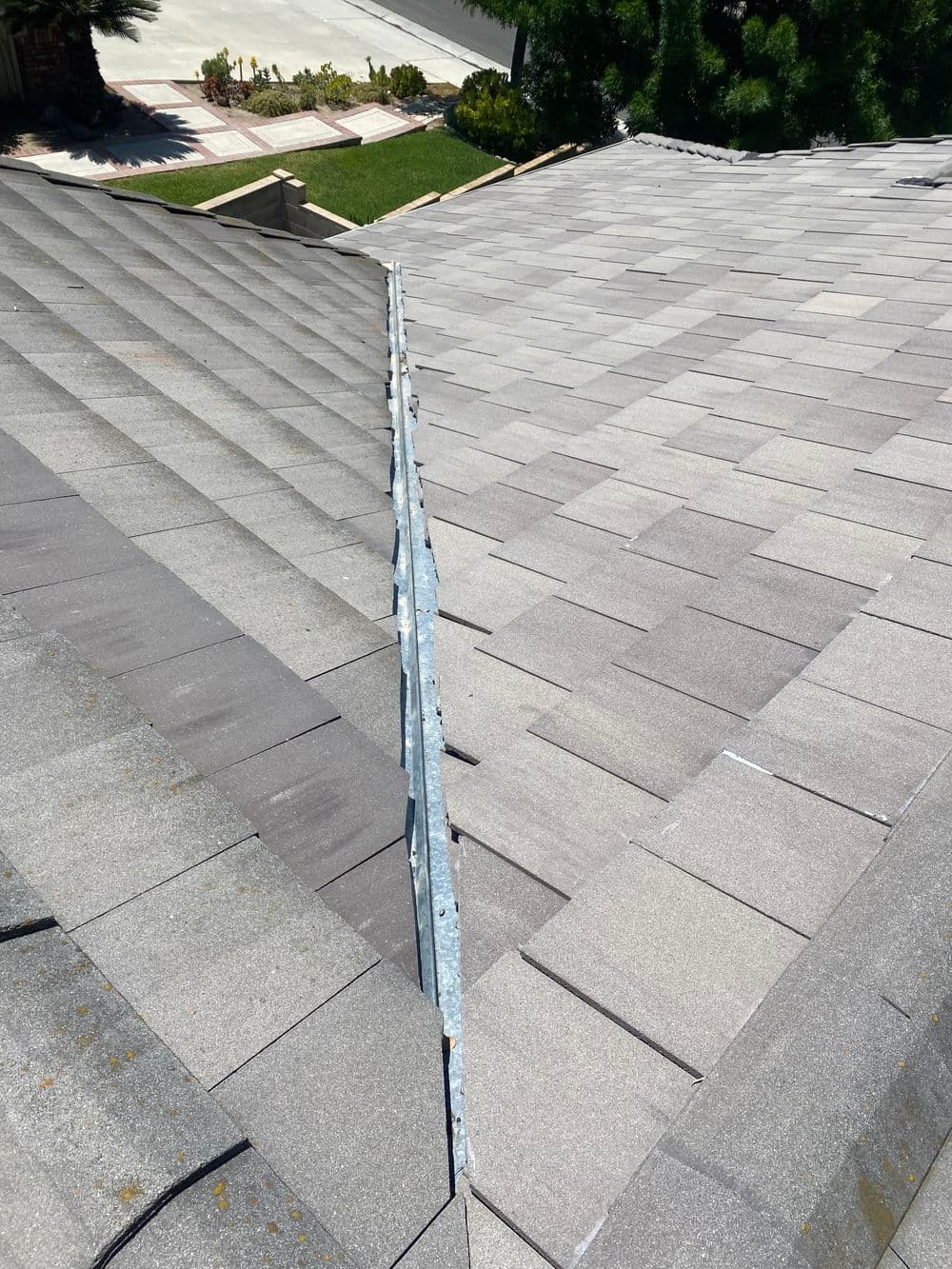 Roof repair showing visible gap between shingles and metal flashing in residential area.