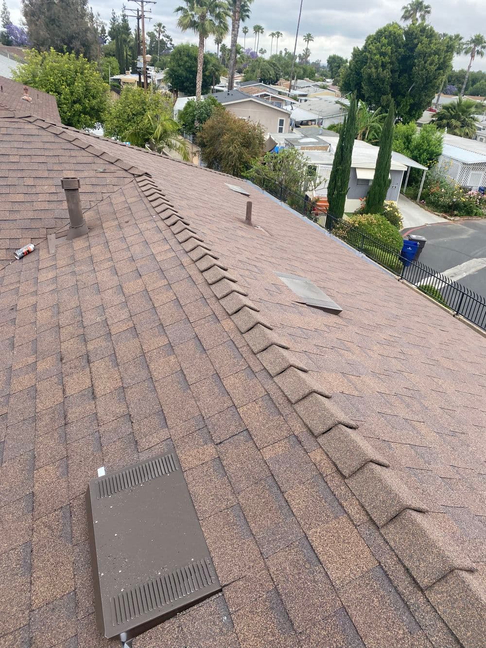 Roofing shingles on a residential home with skylights and surrounding greenery.